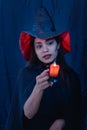 Halloween witch woman portrait holding candle, fashion young woman going to party with spooky costume, makeup scary faces, having