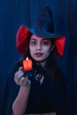 Halloween witch woman portrait holding candle, fashion young woman going to party with spooky costume, makeup scary faces, having