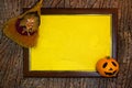 Halloween. Wooden frame with web and yellow paper blank space for text with witch toy on broom and pumpkin. List for recording