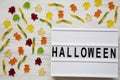 `Halloween` word on lightbox, jelly monsters and worms on white wooden table, top view. From above, overhead