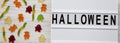 `Halloween` word on modern board, jelly monsters and worms on white wooden background, overhead view. From above, top view, flat