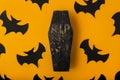 A Halloween yellow background with many bats and black and red coffin in the center. Festive flat lay