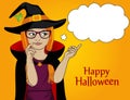 Halloween. A young girl in a hat and a witch costume points thou Royalty Free Stock Photo