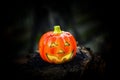 Hallowen pumpkins with shining eyes on a wooden block. Inside has a lighted candle