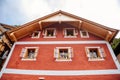 Hallstatt, Austria, 27 August 2021: open wooden window with vase of flowers and statue of orange cat, red and white wall, exterior