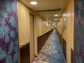 A hallway on a cruise ship with blue geometric patterned carpet and cream colored walls