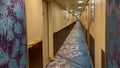 A hallway on a cruise ship with blue geometric patterned carpet and cream colored walls