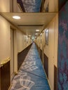 A hallway on a cruise ship with blue geometric patterned carpet and cream colored walls