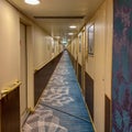 A hallway on a cruise ship with blue geometric patterned carpet and cream colored walls