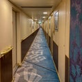 A hallway on a cruise ship with blue geometric patterned carpet and cream colored walls