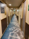 A hallway on a cruise ship with blue geometric patterned carpet and cream colored walls