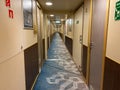 A hallway on a cruise ship with blue geometric patterned carpet and cream colored walls