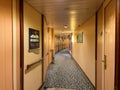 A hallway on a cruise ship with blue patterned carpet and cream colored walls