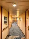 A hallway on a cruise ship with blue patterned carpet and cream colored walls