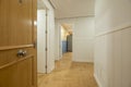 Hallway of a house with a light oak wooden door, wood-like ceramic