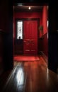 A hallway in a suburban home with a polished dark hardwood floor and a red front door. Royalty Free Stock Photo