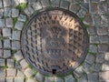 Halmstad, Sweden - August 21, 2022: Halmstad city manhole cover on street with cobblestone pavement, top view