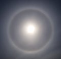 Halo and sun in the sky clouds and a thin layer of cirrus clouds. Royalty Free Stock Photo