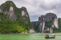 Halong bay limestone cliffs with traditional green fishing boat, UNESCO world natural heritage, Vietnam