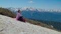 halting on mount slope during hiking, young woman is drinking water and admiring views