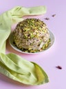 Halva with chopped pistachios and green napkin on pink background