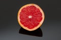 Halve grapefruit on dark shiny surface with reflection Royalty Free Stock Photo