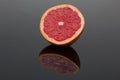 Halve grapefruit on dark shiny surface Royalty Free Stock Photo