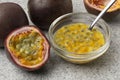 Halved fresh tropical passion fruit and a bowl with passie fruit juice and seeds close up