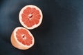 Halved grapefruit on a black background with water drops. Royalty Free Stock Photo