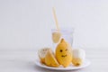 Halved lemon with smile and a glass of lemonade on a white plate on a white background. Royalty Free Stock Photo