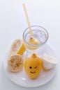 Halved lemon with smile and a glass of lemonade on a white plate on a white background. Royalty Free Stock Photo