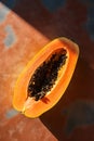 Halved papaya on terracotta floor in bright sunlight with deep shadows. Creative atmospheric image for different concept