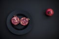 halved pomegranate on black plate,