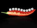 halved red hot chilli pepper with chili seed and the word capsaicin, written with white letter cubes, isolated on black