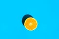 Halved Ripe Juicy Orange on Blue Background. Bright Harsh Sunlight Deep Shadow. Vibrant Neon Colors. Summer Vacation Fashion