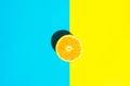 Halved Ripe Juicy Orange on Vivid Duotone Blue Yellow Background. Bright Harsh Sunlight Deep Shadow. Vibrant Neon Colors Royalty Free Stock Photo