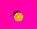 Halved Ripe Juicy Orange on Vivid Fuchsia Pink Background. Bright Harsh Sunlight Deep Shadow. Vibrant Neon Colors