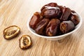 Halves of dates, plate with dried dates on wooden table