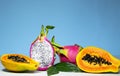 Halves of Fresh organic Dragon Fruit and Papaya on a blue background, creative summer food concept, banner background