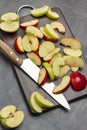 Halves a green apple. Slices of green and red apples and kitchen knife on cutting board