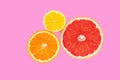 Halves of orange, pink grapefruit and lemon on pink background. Top view of cross section of citrus fruits. Closeup