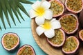 Halves of passion fruits maracuyas, palm leaf and flowers on light blue wooden table, flat lay Royalty Free Stock Photo
