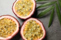 Halves of passion fruits maracuyas and palm leaf on grey table, flat lay Royalty Free Stock Photo
