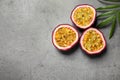 Halves of passion fruits maracuyas and palm leaf on grey table, flat lay. Space for text Royalty Free Stock Photo