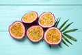 Halves of passion fruits maracuyas and palm leaf on light blue wooden table, flat lay Royalty Free Stock Photo