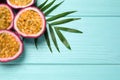 Halves of passion fruits maracuyas and palm leaf on light blue wooden table, flat lay. Space for text Royalty Free Stock Photo