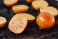 Halves of persimmon fruit on black metal surface.