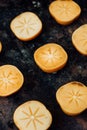 Halves of persimmon fruit on black metal surface.