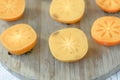 Halves of persimmon fruit on brown wooden background.