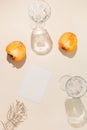 Halves of persimmon fruit with paper card note and two glasse with water on beige pastel background. Summer refreshment